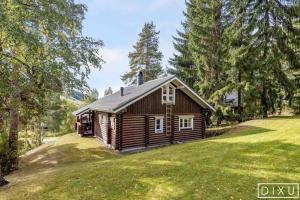 a log cabin in the middle of a grass field at Latvahonka Cottage in Jämsä