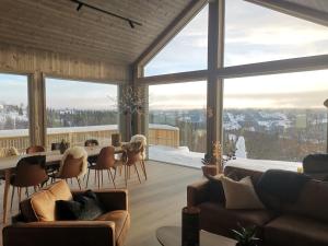 a living room with large windows and a table and chairs at Flott hytte sentralt i Hallingdal in Ål