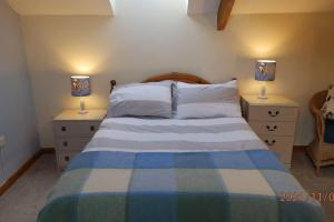 a bedroom with a bed with two lamps on night stands at Spacious 1 bedroom cottage between coasts in North Hill