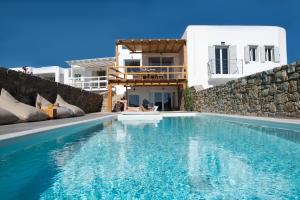 a villa with a swimming pool in front of a building at Villa Costa by Whitelist Mykonos in Ftelia
