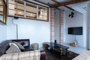 a living room with a couch and a tv at Ático con terraza y vistas al mar. in A Coruña