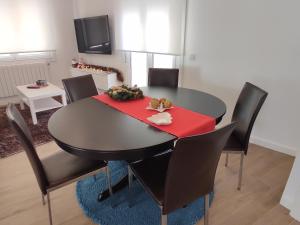 uma mesa de jantar com cadeiras pretas e um guardanapo vermelho em Apartamento Moaña La Playa, recién reformado em Moaña