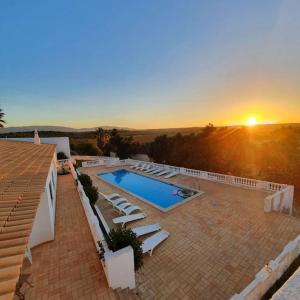 a house with a swimming pool and a sunset at Blue Skies Villas 1&2 in Mexilhoeira Grande