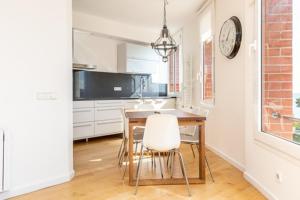 eine Küche mit einem Tisch und Stühlen sowie einer Uhr an der Wand in der Unterkunft Idyllic apartment in BCN beach in Barcelona