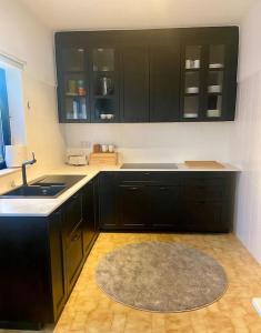 a kitchen with black cabinets and a sink and a rug at Blue Skies Villas 1&2 in Mexilhoeira Grande