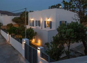 Una casa blanca con luces en el costado. en Ruby's summer house with spacious garden and free parking, en Gavrion