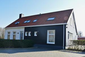 uma casa a preto e branco com um telhado vermelho em Woning zeldenrust 6 em Oostkapelle