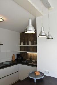 a kitchen with a sink and two lights and a table at Woning zeldenrust 6 in Oostkapelle