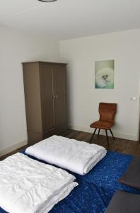 um quarto com uma cama branca e uma cadeira em Woning zeldenrust 6 em Oostkapelle