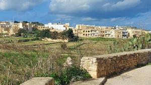 a city with a stone wall and buildings in the background at Trilogy, Ample Penthouse, Gozo in Kerċem