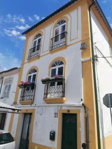 um edifício amarelo e branco com janelas e uma porta em Casa da Joana by Portus Alacer em Portalegre