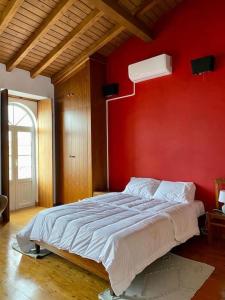 um quarto com uma parede vermelha e uma cama em Casa da Joana by Portus Alacer em Portalegre