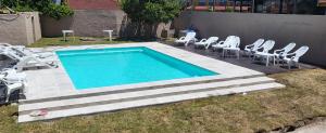 una piscina con sedie bianche e un mucchio di cose di Hotel El Velero a Villa Gesell