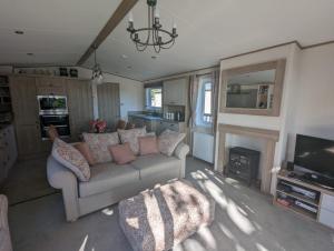 a living room with a couch and a television at STUNNING LUXURY Caravan on edge of New Forest on SHOREFIELD Country Park ENTERTAINMENT AND LEISURE PASSES INCLUDED in Milford on Sea