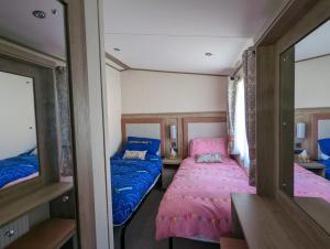 um pequeno quarto com 2 camas e um espelho em STUNNING LUXURY Caravan on edge of New Forest on SHOREFIELD Country Park ENTERTAINMENT AND LEISURE PASSES INCLUDED em Milford on Sea