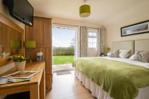 a bedroom with a bed and a tv and a window at The Country Lodge at Hill House Farm Cheshire in Tarporley