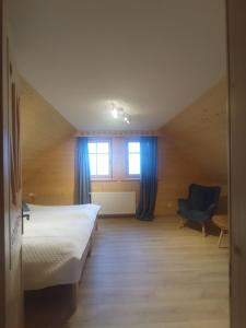 sypialnia z łóżkiem, krzesłem i oknem w obiekcie Dom z bala w mieście Lipowa