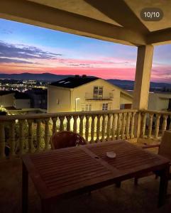a wooden table on a balcony with a sunset at Apartmani Nina in Šibenik