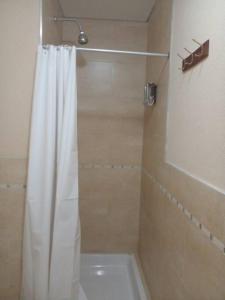 baño con ducha con cortina blanca en Departamento amoblado en Nordelta. en Benavídez