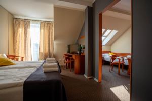 ダルウフコにあるTramontana Family & Wellnessのベッド、テーブル、椅子が備わるホテルルームです。