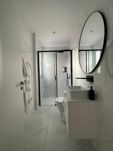 a white bathroom with a sink and a mirror at Ajuda Luxury Appartments in Lisbon