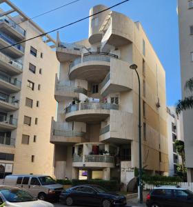 een gebouw met balkons en auto's die ervoor geparkeerd staan bij Chilling in Netanya in Netanya