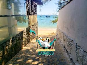 a sign for a beach resort with a pelican sitting on a chair at Sabatico Beach House in Búzios