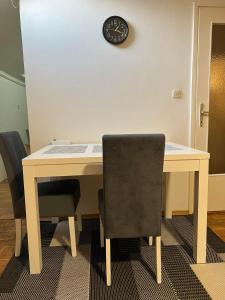 a desk with two chairs and a clock on a wall at Apartman Centar Travnik in Travnik
