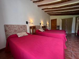 two beds in a room with pink sheets at Cortijo EL COSIO in Benamaurel