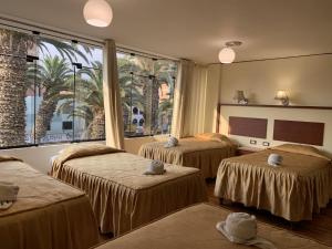 una camera con tre letti e una grande finestra di HOTEL AVENIDA a Tacna