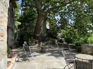 a patio with chairs and tables and a tree at Palio Eleotrivio Guesthouse in Agios Lavrentios