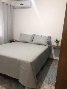 Cama en habitación con pared blanca en Apartamento confortável a três quadras do mar, en Balneário Camboriú