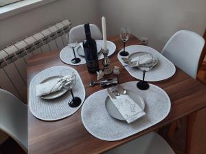 a wooden table with plates and wine glasses on it at Apartman Đorđević in Kraljevo