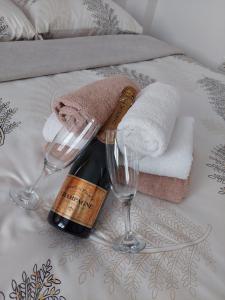 a bottle of wine and two glasses on a bed at Apartman Đorđević in Kraljevo