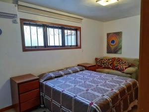 1 dormitorio con cama, sofá y ventana en Casa dos beija Flores, 80 mts da praia do centro, en Bombinhas