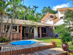 un patio trasero con una terraza de madera y una casa en Casa dos beija Flores, 80 mts da praia do centro, en Bombinhas