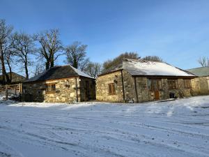 ein altes Steingebäude mit Schnee auf dem Boden in der Unterkunft The Stable in Saint Clether