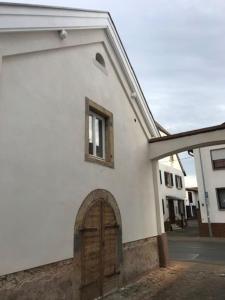 ein weißes Gebäude mit einer Tür und einem Fenster in der Unterkunft Ferienhaus „uff‘m Woikeller“ in Meckenheim