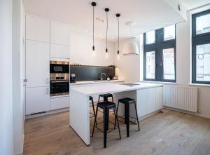 una cocina con armarios blancos y una isla con taburetes en Les Camuches en Tournai