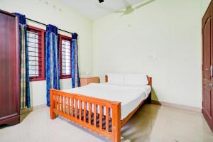 a bedroom with a wooden bed and two windows at Shalom Palace in Cochin