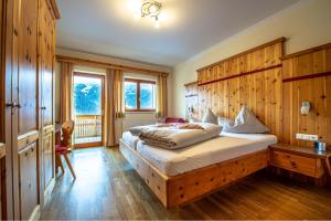 1 dormitorio con 1 cama con pared de madera en Hotel Raunig en Bad Kleinkirchheim