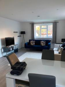 a living room with a blue couch and a tv at Ella Court Devon in Torquay