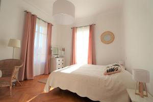 a white bedroom with a bed and a window at Maison familiale niçoise avec terrasse in Nice