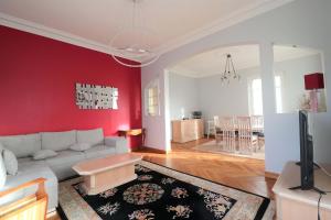 a living room with a couch and a red wall at Maison familiale niçoise avec terrasse in Nice