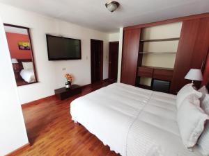 a bedroom with a white bed and a flat screen tv at Kur Hotel & Bio Spa in Duitama