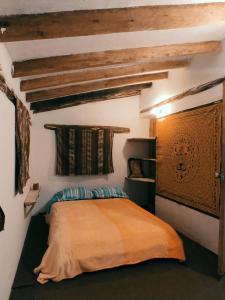 a bedroom with a bed in a room with wooden ceilings at Wallpari Sonqo Hospedaje Medicina temazcal in Pisac