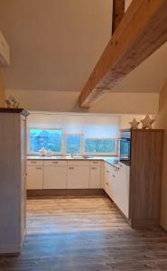 a large kitchen with white cabinets and windows at Ferienwohnung Sternenstube in Völkenroth