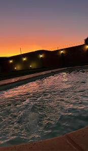 una piscina de agua con una puesta de sol en el fondo en Monoambiente El Pinar Parque y Pileta Privada en San Luis