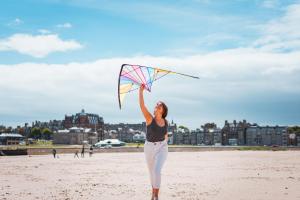a woman is holding a kite on the beach at Old Course Hotel St Andrews in St. Andrews