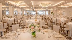 セント・アンドルーズにあるオールド コース ホテル セント アンドリューズの白いテーブルと椅子、シャンデリアが備わる宴会場